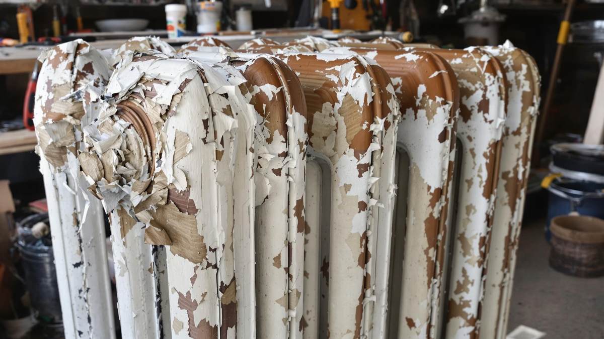 Radiateur en fonte avec peinture écaillée partiellement retirée dans un atelier