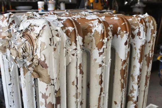Radiateur en fonte avec peinture écaillée partiellement retirée dans un atelier